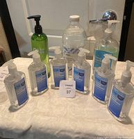 Front view of all 9 hand sanitizer bottles showing six Amazon-branded small bottles and three larger assorted brand bottles