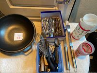 Two large new ES wok pans shown beside kitchen tools, silverware box