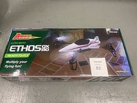 Top view of the sealed box showing Ares Ethos QX30 ultra-micro quadcopter with video camera, branding, and ready-to-fly status.