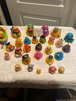 Top-down view of all rubber toys including duckies, octopus, and small characters arranged on a white surface