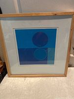 Framed abstract lithograph artwork featuring blue and purple circular design.