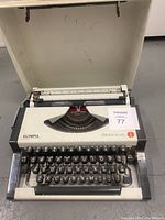 Front view of Olympia Traveller de Luxe typewriter showing QWERTY keyboard and keys, typebars, and model branding