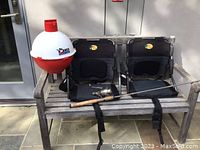 Wood bench with two black Bass Pro fishing chairs, fishing rod with reel on the bench, and Big Bobber floating cooler attached to the bench arm.