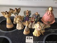 Photo showing a group of ten assorted angel figurines in various poses and colors on a black surface.