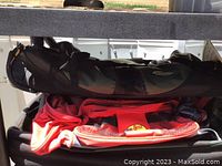Black fishing rod carrying case with compartments and red Bass Pro Shops duffle bag stacked on a shelf.