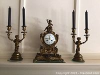 Front view of the complete clock garniture set with clock center and candleholders on either side, showing the overall size and design.