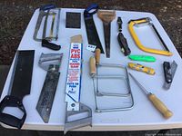 Wide view of assorted hand saws and cutting tools arranged on table