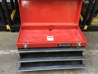 Open view of Husky red metal tool chest showing the top lid open and four empty drawers pulled out.