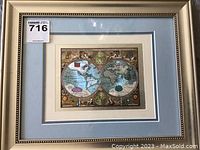 Photo of first framed metal etching showing dual hemispheres of world map with gold accented frame and double matting.