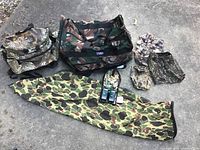 Full view of all items showing two radios, multiple camouflage bags including duffel, backpack and bow case, and smaller pouches.