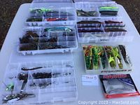 Photo showing four plastic tackle boxes containing various soft plastic worms, crawfish imitation lures, fishing hooks, and a packaged set of soft fishing baits.