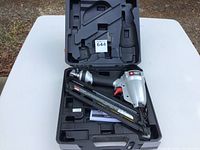 Porter-Cable finish nailer in open hard plastic case on white table outdoors, showing the tool, its magazine, and handles.