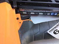 Close-up of the textured handle and safety features of the orange RIDGID framing nailer.