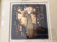 Close-up of the gold leaf photographic print showing the Chrysler Building and surrounding architecture with foliage in the foreground.