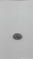 Oval cabochon black rutilated quartz with visible black tourmaline needle inclusions, lying on white background
