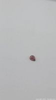 Pear-shaped cabochon cut deep cherry red Almandine garnet gemstone placed on plain white background, showing size and color.