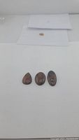 Three polished mahogany jasper cabochons displayed on a white surface, showing their size and shape.