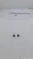 Front view of the sapphire stud earrings showing the blue stones and silver setting on white background