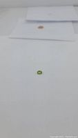 Small apple green natural peridot gemstone on white background, photographed from above for size and color reference.