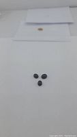 Three oval cabochon cut natural jet black onyx gemstones placed on white surface, showing size and shape.