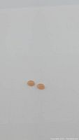Two small oval peach moonstone cabochons on white background, showing smooth polished surface and soft peach color.