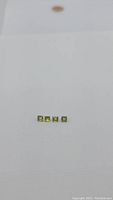 Four square princess cut peridot gemstones displayed in a row on white background.
