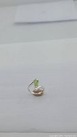 Close-up image of a silver ring with a pear-shaped apple green Peridot gemstone.