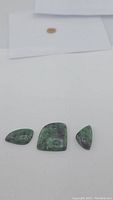 Three polished natural ruby zoisite stones on white background showing their irregular shapes and ruby inclusions.