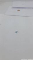 Close-up photo of a single oval cut sky blue topaz gemstone on a white surface, highlighting its clarity and color.