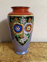 Full view of hand painted Japanese vase showing floral design with black and lavender background and a reddish rim on top