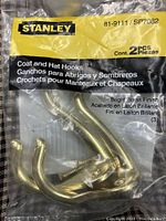Close-up photo of a sealed package of Stanley brass finish coat and hat hooks containing 2 hooks.
