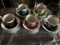 View of all five Royal Albert teacup and saucer sets arranged on a table, showing various colors and gold detailing.