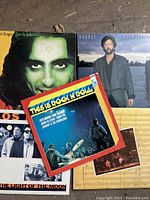 Photo of the five vinyl records partially overlaid showing Alice Cooper album, This Is Rock N' Roll compilation, and other rock albums.