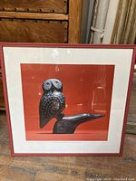 Full view of the framed print showing the owl on the seagull sculpture with an orange background and orange frame.