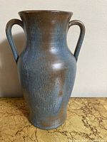 Front view of the vase showing the blend of blue and brown glaze and two handles.