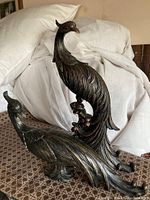 Pair of resin bird sculptures with patina finish on white fabric background
