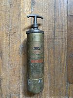 Overall front view of the vintage fire extinguisher showing the full cylinder, T-shaped top handle, and label.
