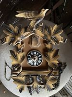 Full view of the vintage carved wooden German cuckoo clock showing entire front with leaves and bird.