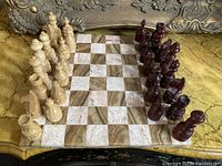 Photo showing entire marble chessboard with wooden chess pieces set up on the board, showing alternating marble squares and wood carved pieces in light and dark finishes.