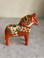 Front angled side view of the vintage orange Dala horse, showing floral painted decorations.