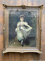 Full view of vintage shadowbox framed print portrait of a young girl in a white dress with ornate gold-tone corner adornments on the frame.