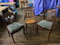 Three vintage chairs showing two matching upholstered seat chairs and one caned seat chair, all wooden with carved details.