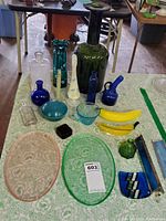 Image showing art glass items including uranium glass dish, glass bananas, multiple glass vases and bottles, small bowls, and stained glass kaleidoscopes