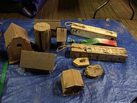 Overview photo of all six birdhouses and additional woodcraft decor items on blue tarp