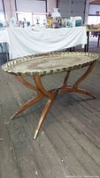 Full side view of brass tray table on folding wood legs