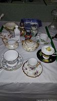 Display of all items including cups, saucers, lidded jars, shaker, hair receiver, bowls and vase.