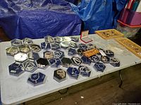 Full view of a white folding table with multiple hexagonal display cases containing various costume jewelry pieces including bracelets and necklaces.