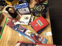 Full lot overview showing boxed Gorby doll, NE Patriots lunch box, Disney plate, Hangman games, Batman figure, and Spiderman fishing kit