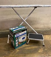 Photo showing ironing board legs, Robitussin Cool Mist Humidifier sealed box, and Urceri step stool