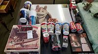 Wide view of the lot on table including Star Wars game, poster, collectible cups, and Coca Cola cans.